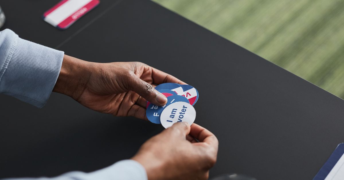 A close-up of hands holding voter stickers, symbolizing civic engagement.
